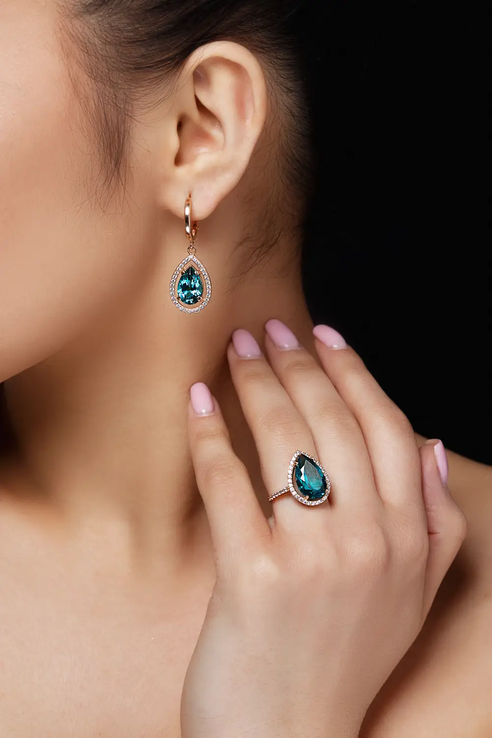 Model wearing earrings and a ring with blue gemstones
